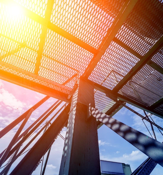 Die Sonne scheint durch die Metallstruktur eines Gebäudes und erzeugt interessante Licht- und Schatteneffekte.
