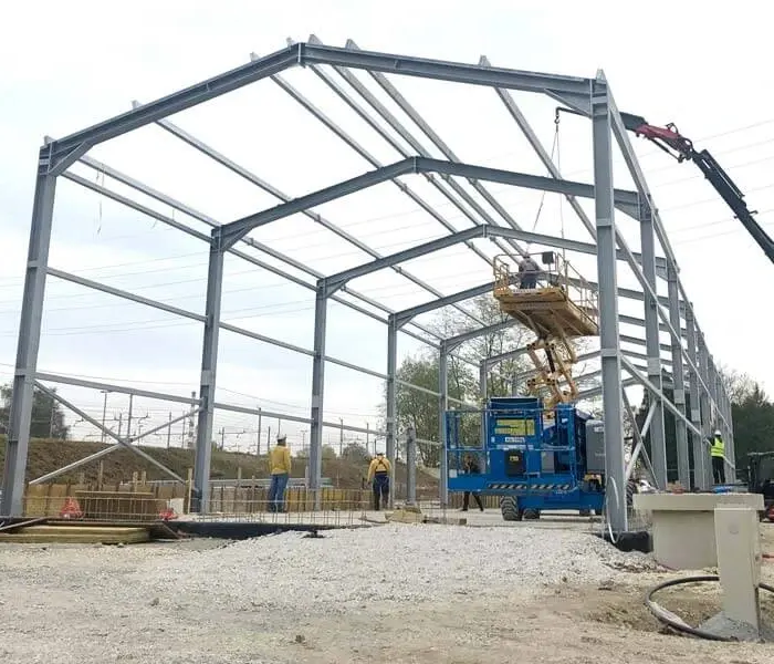 Stahlkonstruktion im Bau, sichtbar auf einem Parkplatz, zeigt industrielle Bauarbeiten und Materialien.